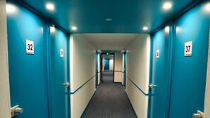 Un couloir d’hôtel avec des portes bleues numérotées 32, 31, 37 et 38.