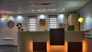 Un comptoir d’accueil avec un revêtement en bois, une horloge et un panneau affichant le menu.