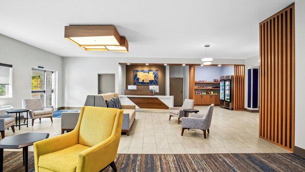 A hotel lobby with a reception desk, seating area, and a kitchenette.