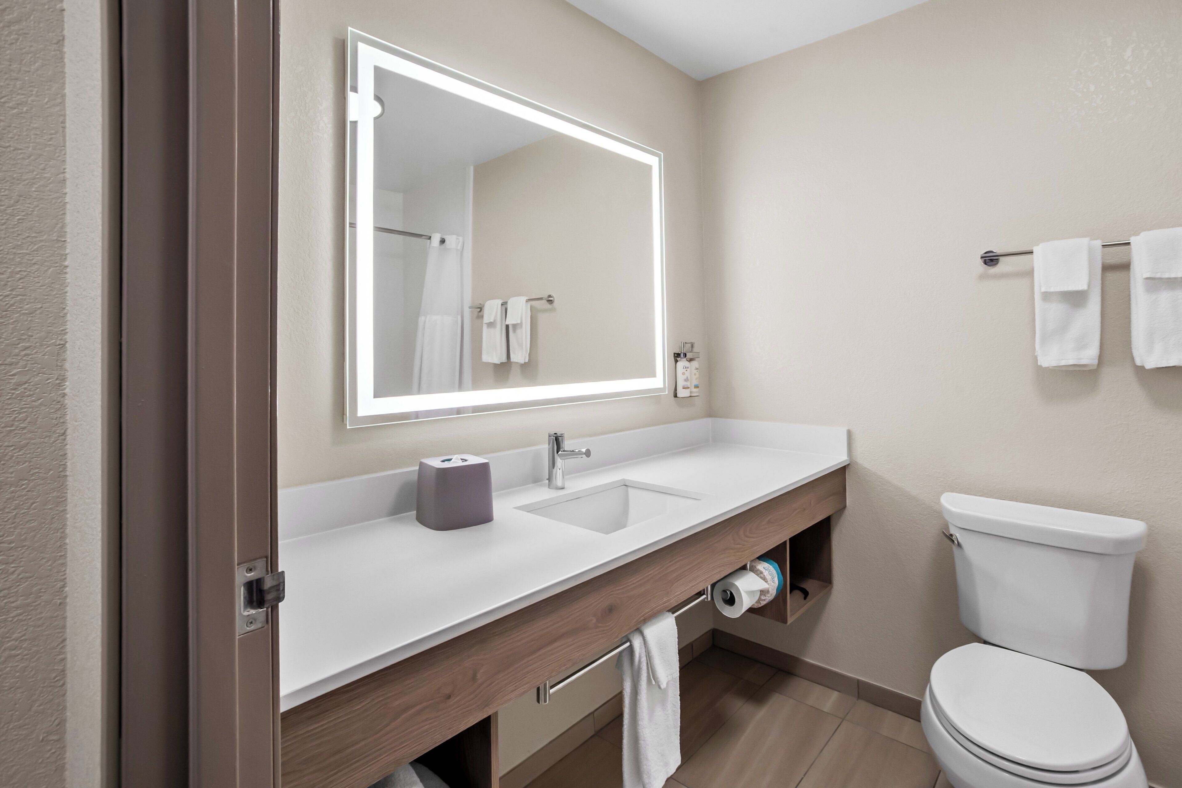 A modern bathroom with a white sink, mirror, and toilet.
