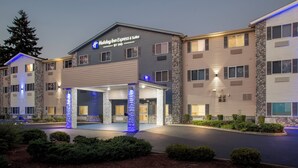 A Holiday Inn Express & Suites building with a stone facade, multiple windows, and a well-lit entrance.