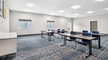 Une salle de conférence avec une longue table, des chaises et un tableau blanc.