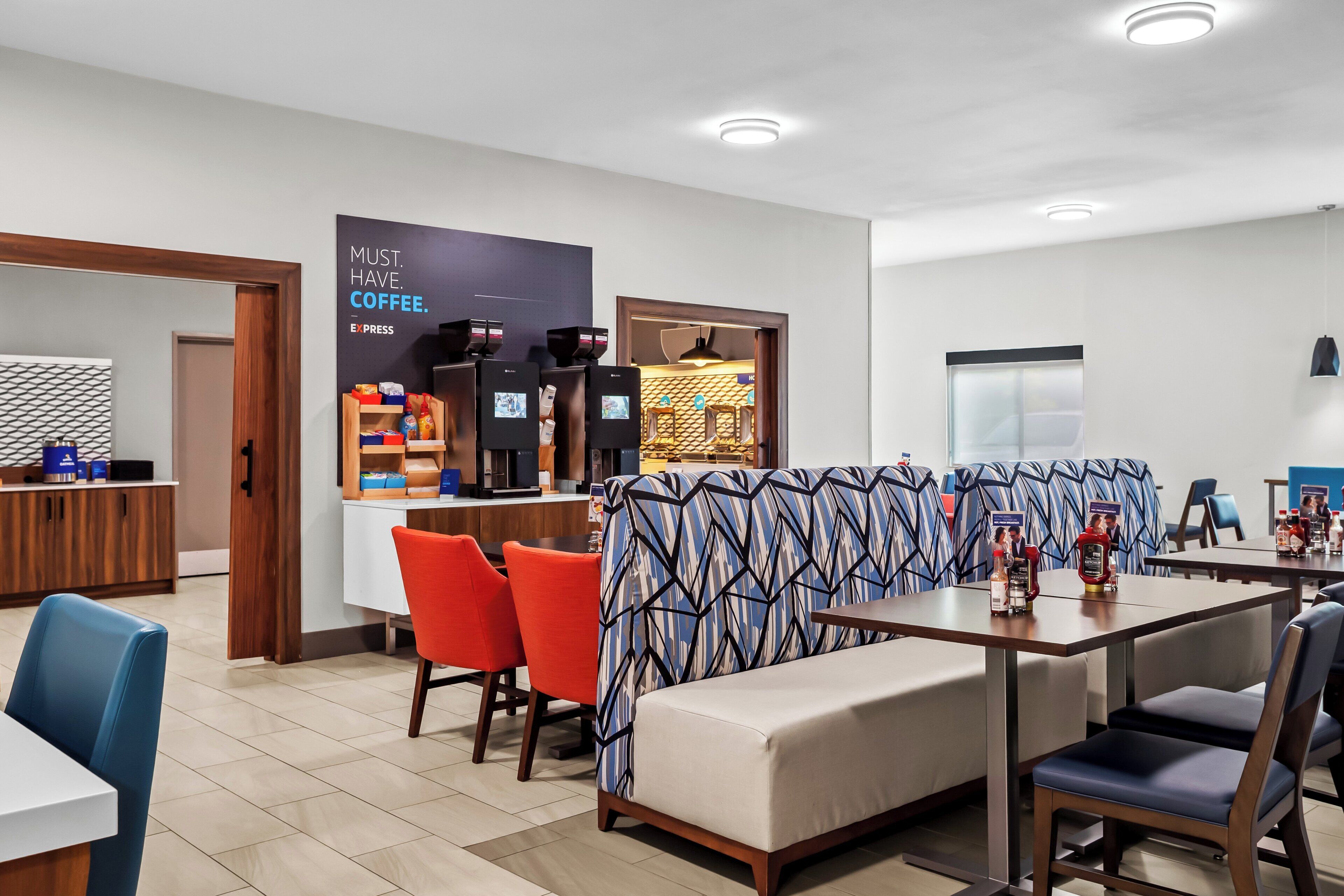 A modern hotel lobby with a coffee bar, seating area, and a reception desk.