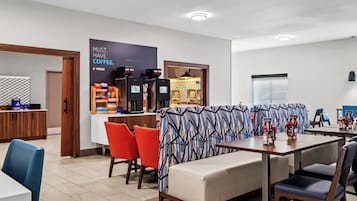 A modern hotel lobby with a coffee bar, seating area, and a reception desk.