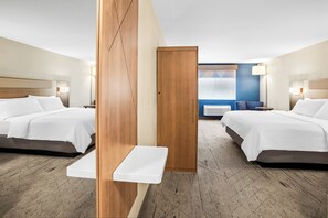 Habitación de hotel con dos camas, una mesita y vista a la ciudad por la ventana.