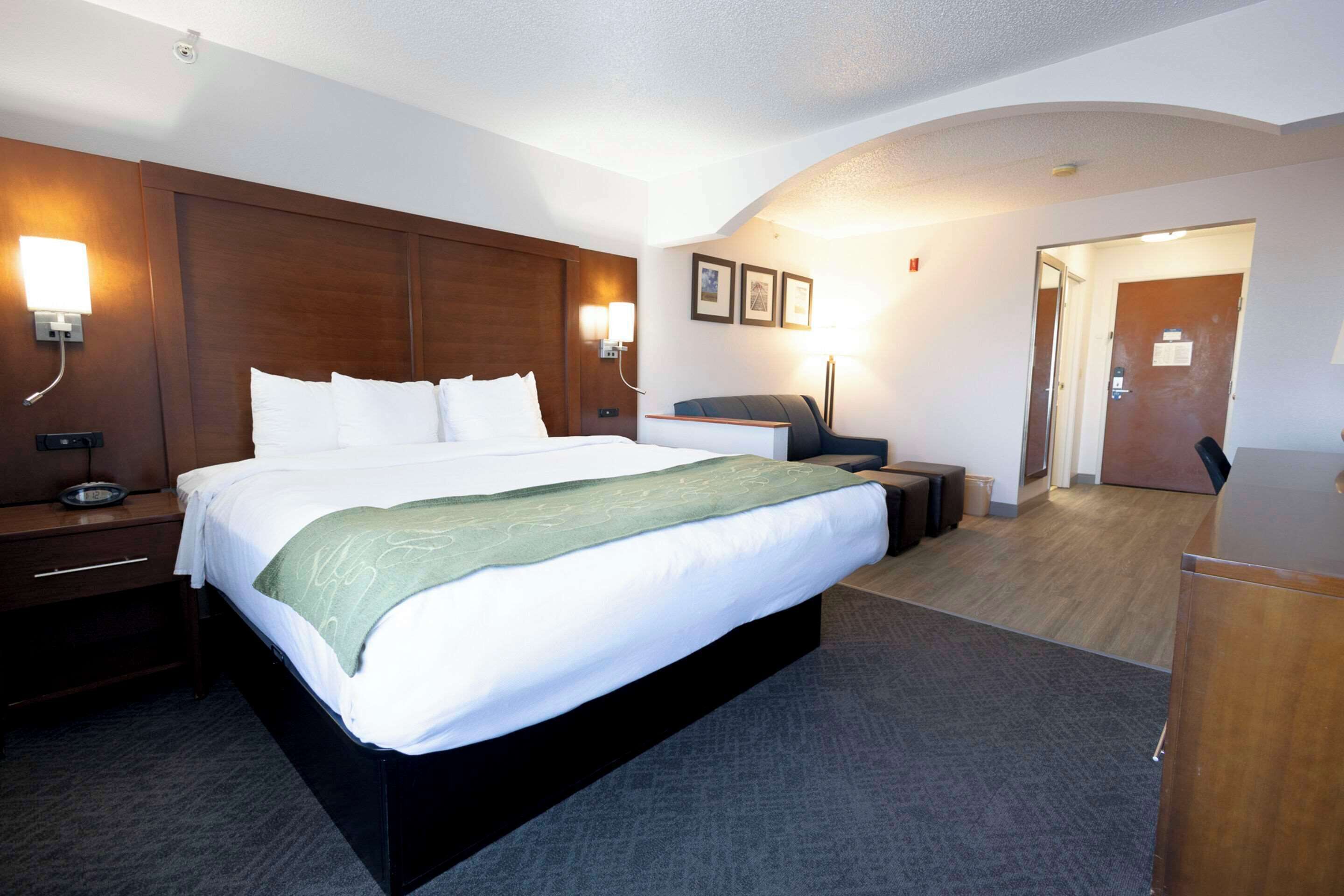 Una habitación de hotel con una cama grande, mesitas de noche, un escritorio y una silla.