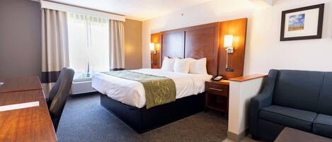 Een hotelkamer met een bed, een bureau, een stoel, een bank en een raam met gordijnen.