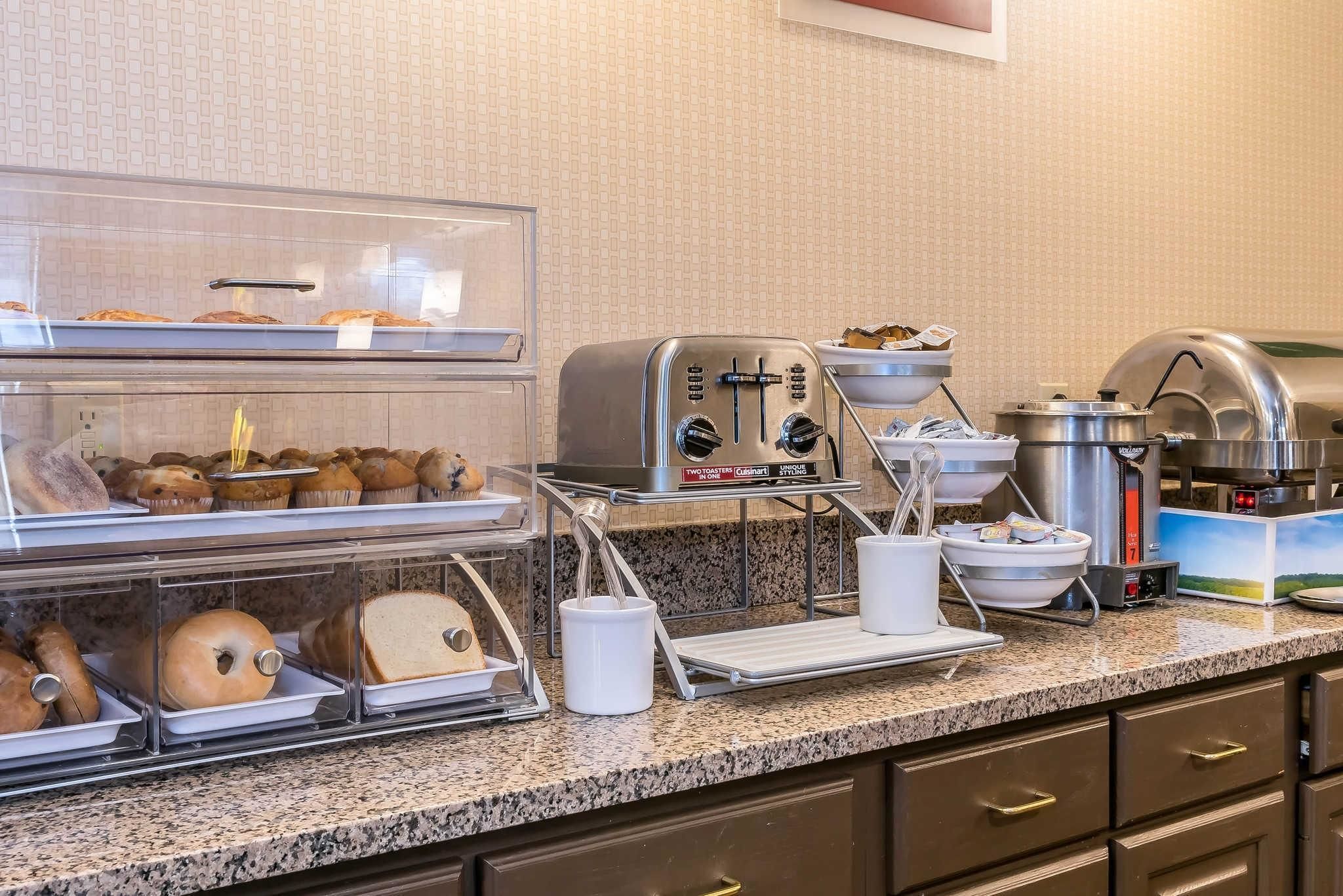 Buffet de café da manhã com diversos pães, uma torradeira e uma cafeteira.