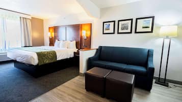 Une chambre d’hôtel avec un lit, un canapé, une table basse et une lampe sur pied.