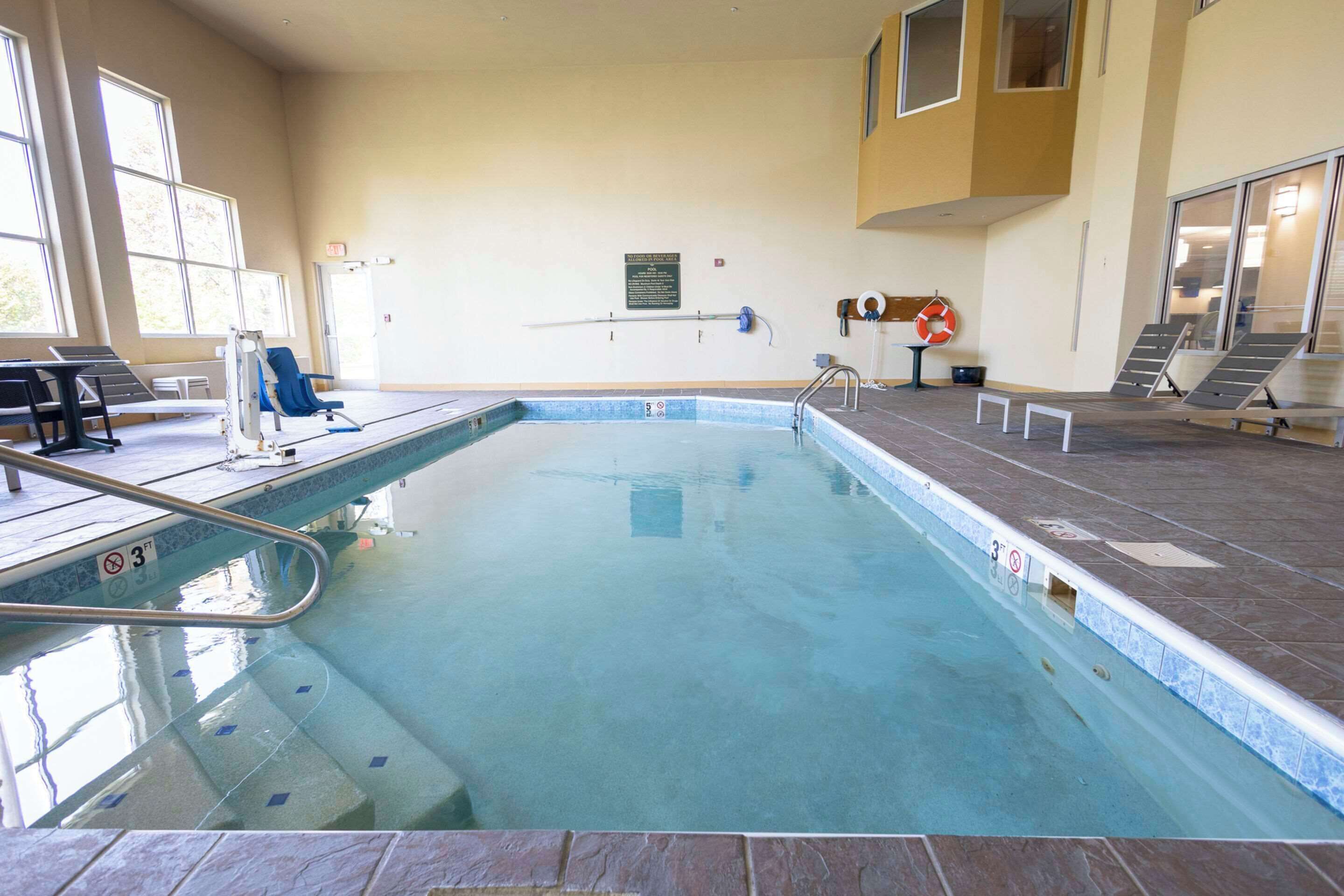 Une piscine intérieure avec un sol carrelé, une bouée de sauvetage et un panneau sur le mur.