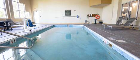 Une piscine intérieure avec un sol carrelé, une bouée de sauvetage et un panneau sur le mur.