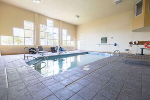 Una piscina interior con paredes de vidrio transparente, suelo de baldosas y un flotador en la pared.