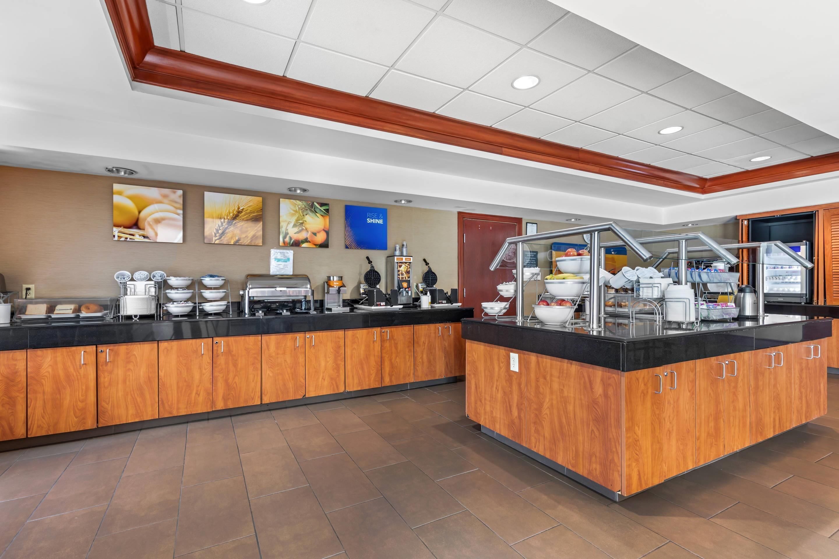 A breakfast bar with wooden cabinets, a black countertop, and various food items.