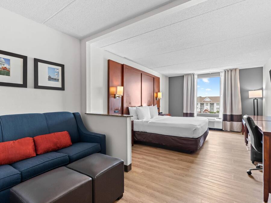 A hotel room with a bed, a sofa, a desk, and a TV.