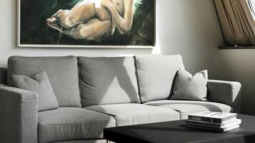 A modern living room with a grey sofa, a black coffee table, and a framed painting above the sofa.