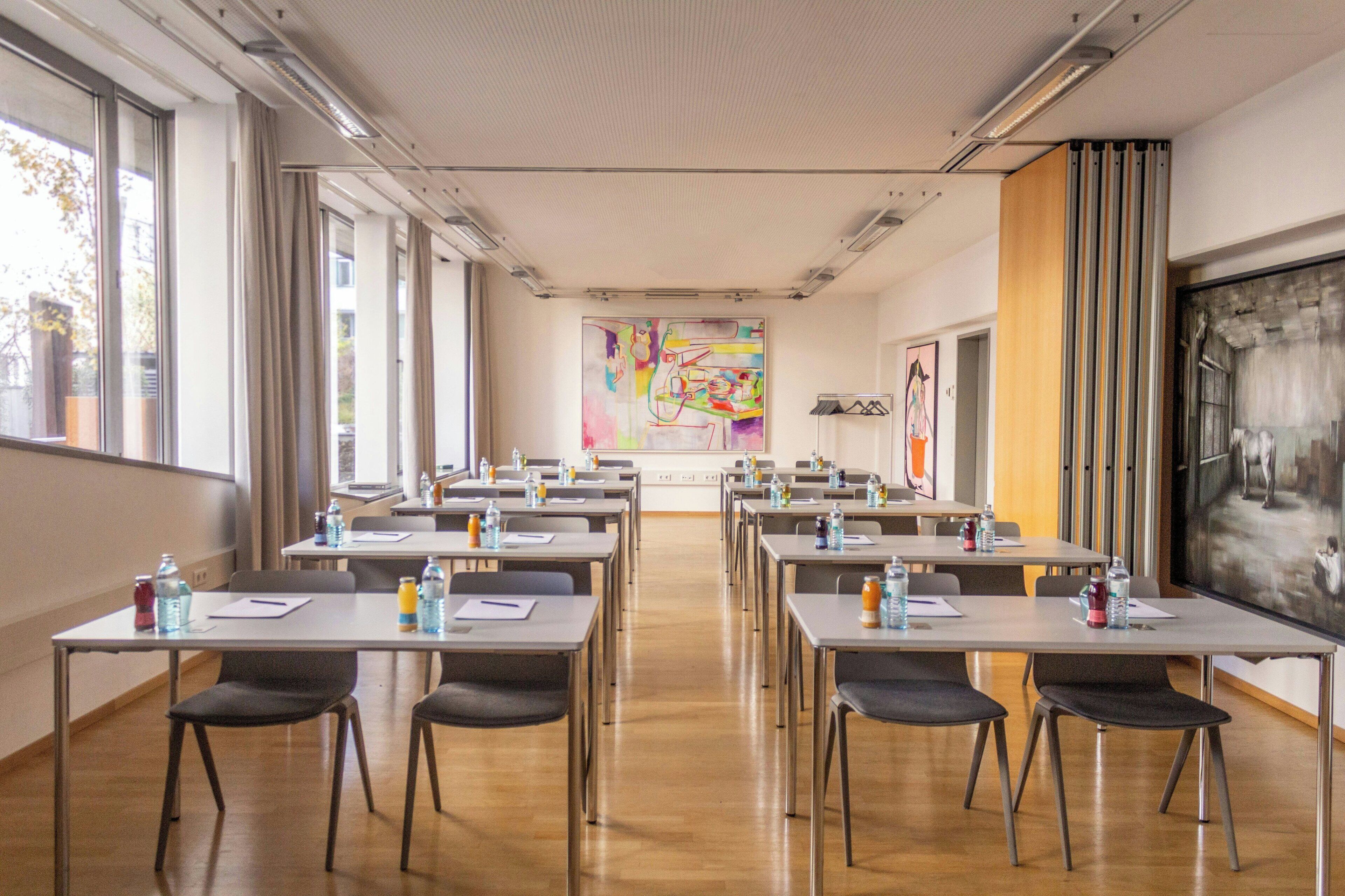 Una sala conferenze con tavoli, sedie e un grande schermo.
