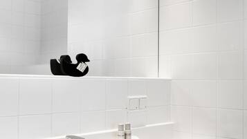 A modern bathroom with a white sink, mirror, and tiled walls.