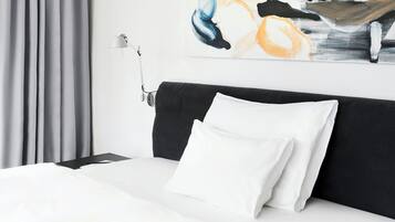 A hotel room with a bed, a nightstand, a lamp, and a painting on the wall.