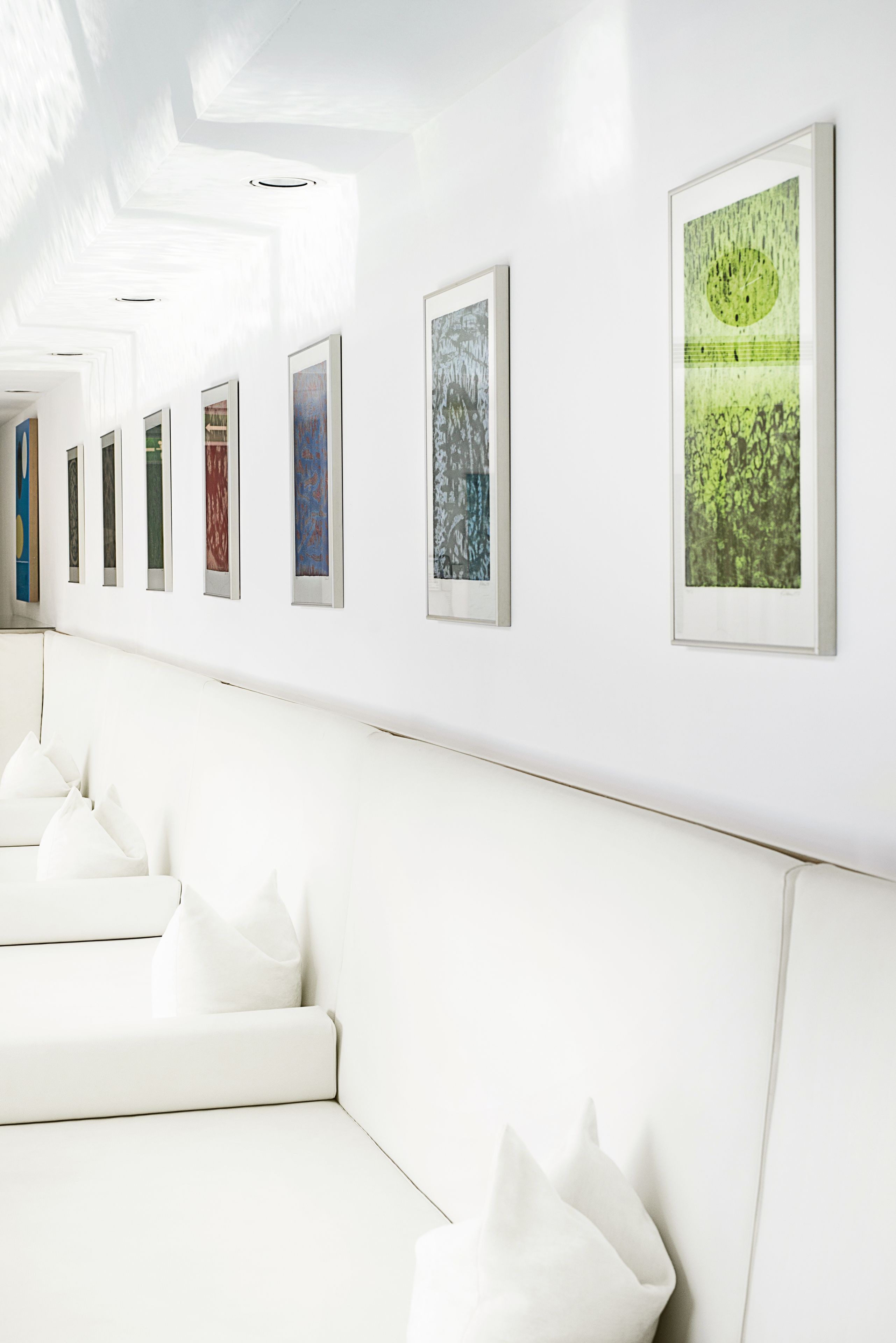 Un intérieur moderne avec un canapé blanc et des œuvres d’art accrochées au mur.