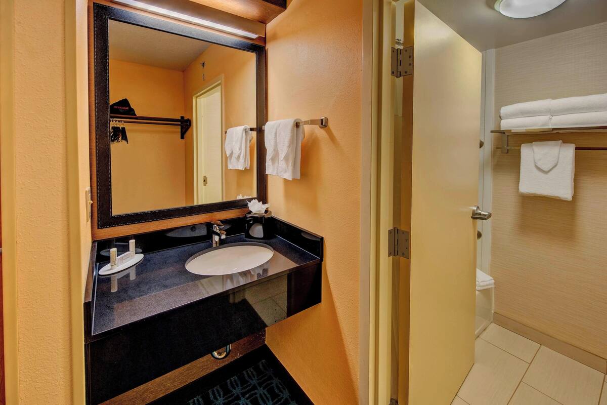 A bathroom with a black sink, a mirror, and a towel rack.