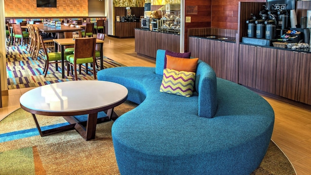 A modern lounge area with a blue sofa, a round table, and a colorful carpet. - Fairfield Inn & Suites by Marriott Near Universal Orlando (Orlando)