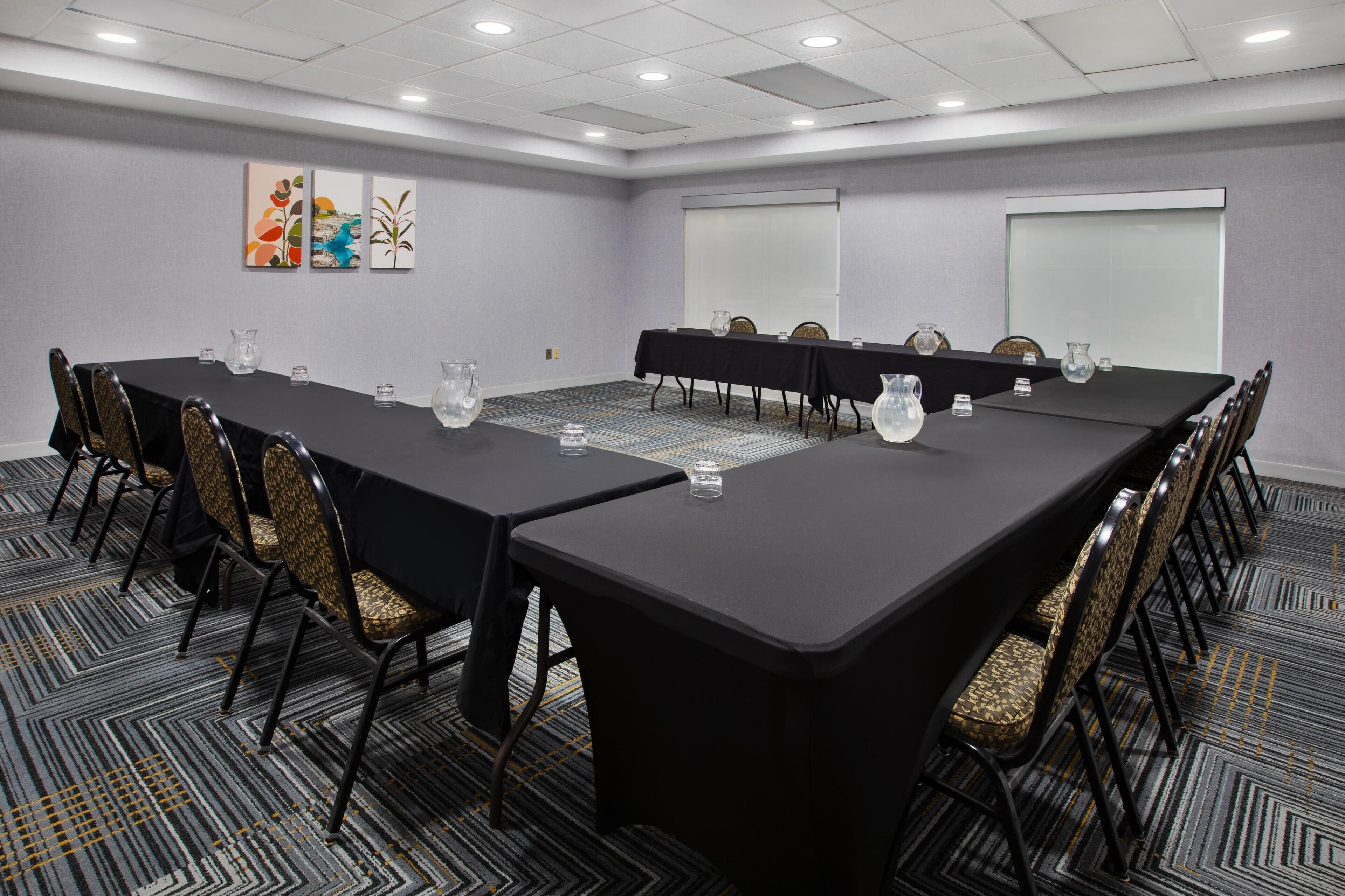 A conference room with a long table, chairs, and a projector screen.