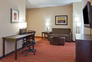 A hotel room with a desk, office chair, sofa, and TV. - Homewood Suites by Hilton Sioux Falls (Sioux Falls)