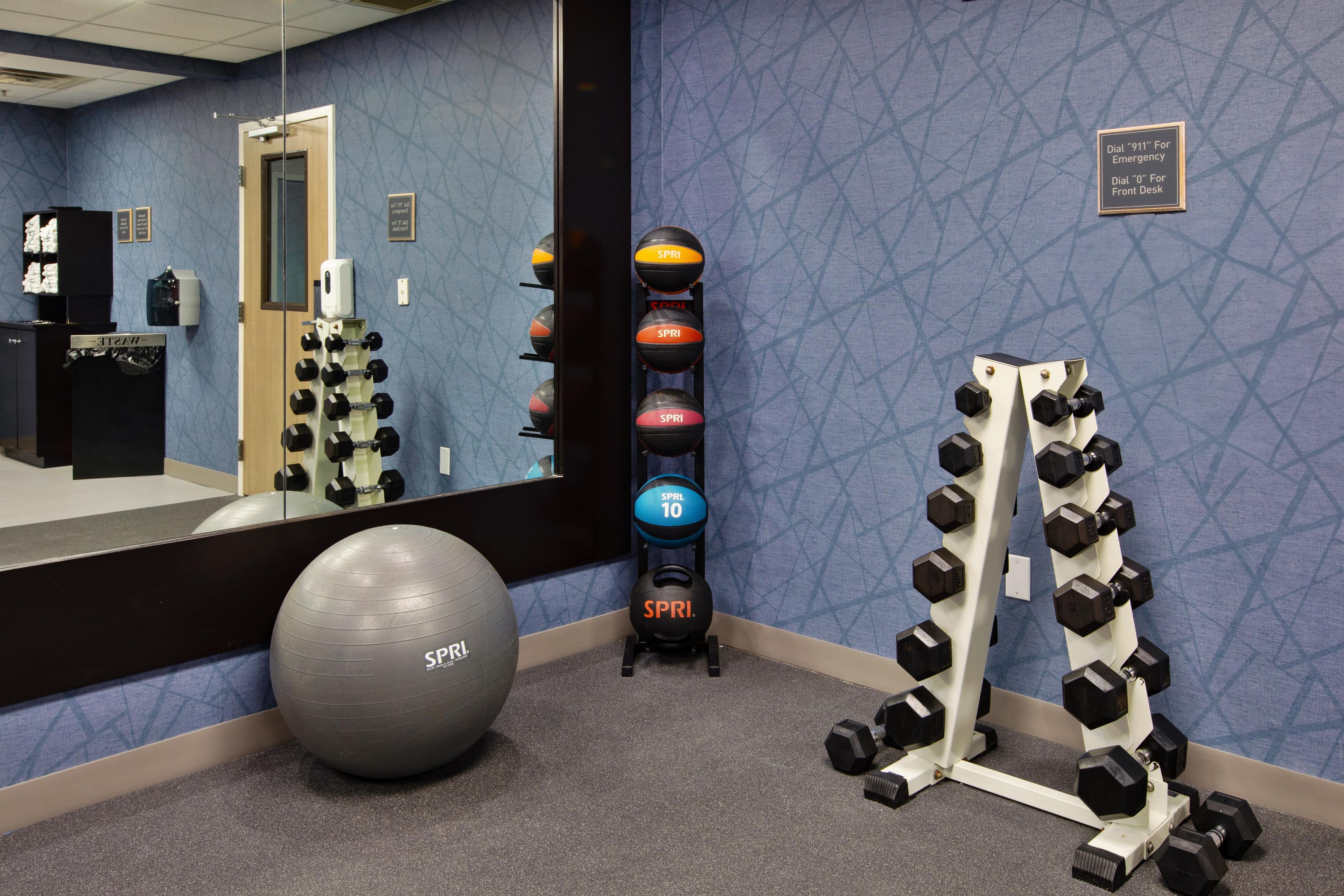 Un gimnasio con equipo de ejercicio, un espejo grande y un cartel en la pared.