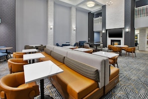 Un restaurante moderno con una mesa común alargada, cabinas individuales y una chimenea.