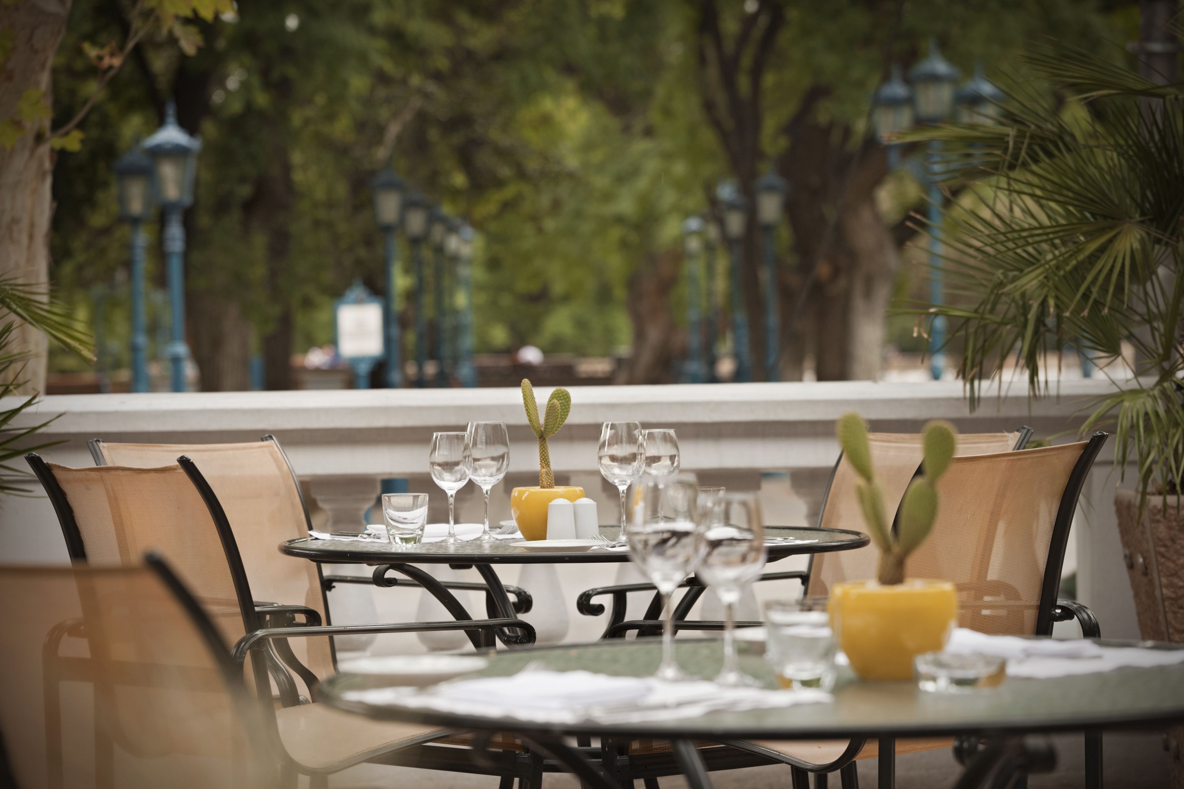 A table set for dining with chairs, a yellow vase, and wine glasses.