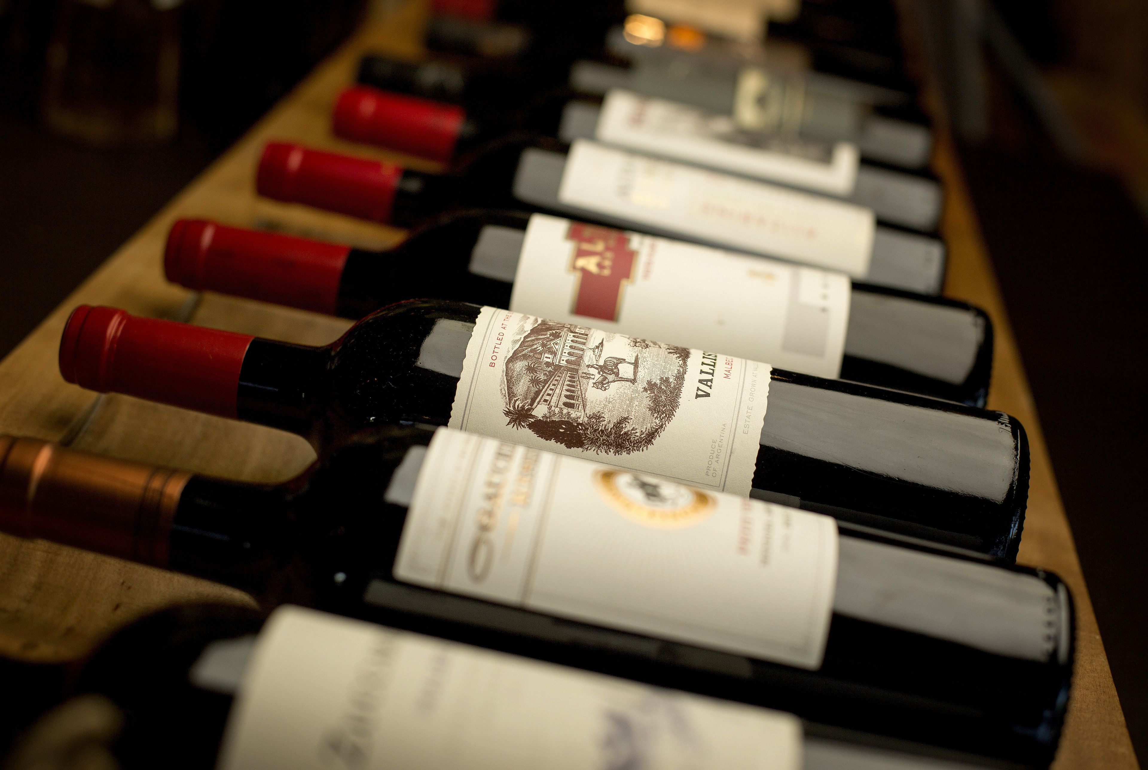 Varias botellas de vino con etiquetas sobre una superficie de madera.