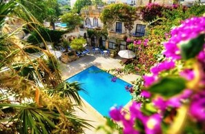 Relax by the serene pool surrounded by lush greenery and vibrant flowers, with lounge chairs and umbrellas for a comfortable stay.