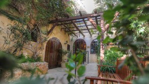 Une cour dotée d’une pergola en bois, de murs en pierre et de portes cintrées.