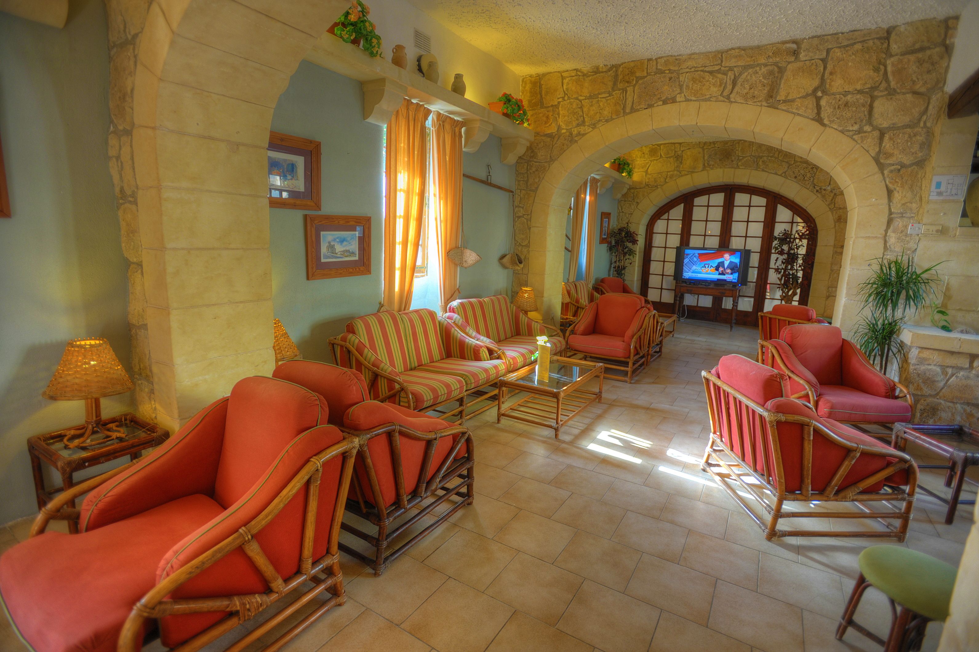 A spacious living room with wicker furniture, stone arches, and a television.