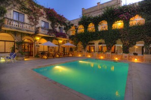 Relax by the serene pool surrounded by traditional architecture and lush greenery.