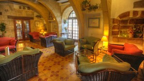 Un hall d’entrée spacieux, doté de meubles en osier, d’une cheminée et de murs en pierre en forme d’arc.