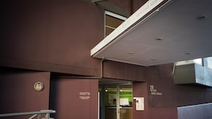 A building entrance with a metal staircase, a glass door, and a sign indicating '219 Kent Street Serviced Apartments'.