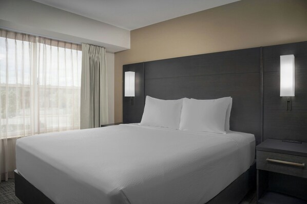 A hotel room with a large bed, a nightstand, and a window with sheer curtains. - Residence Inn by Marriott Spokane East Valley (Spokane Valley)