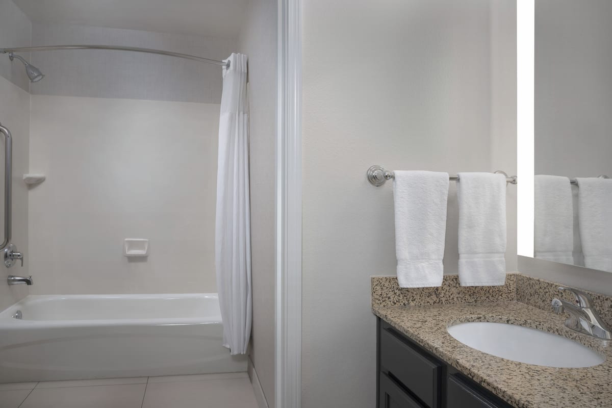 A bathroom with a bathtub, a sink, and a mirror.