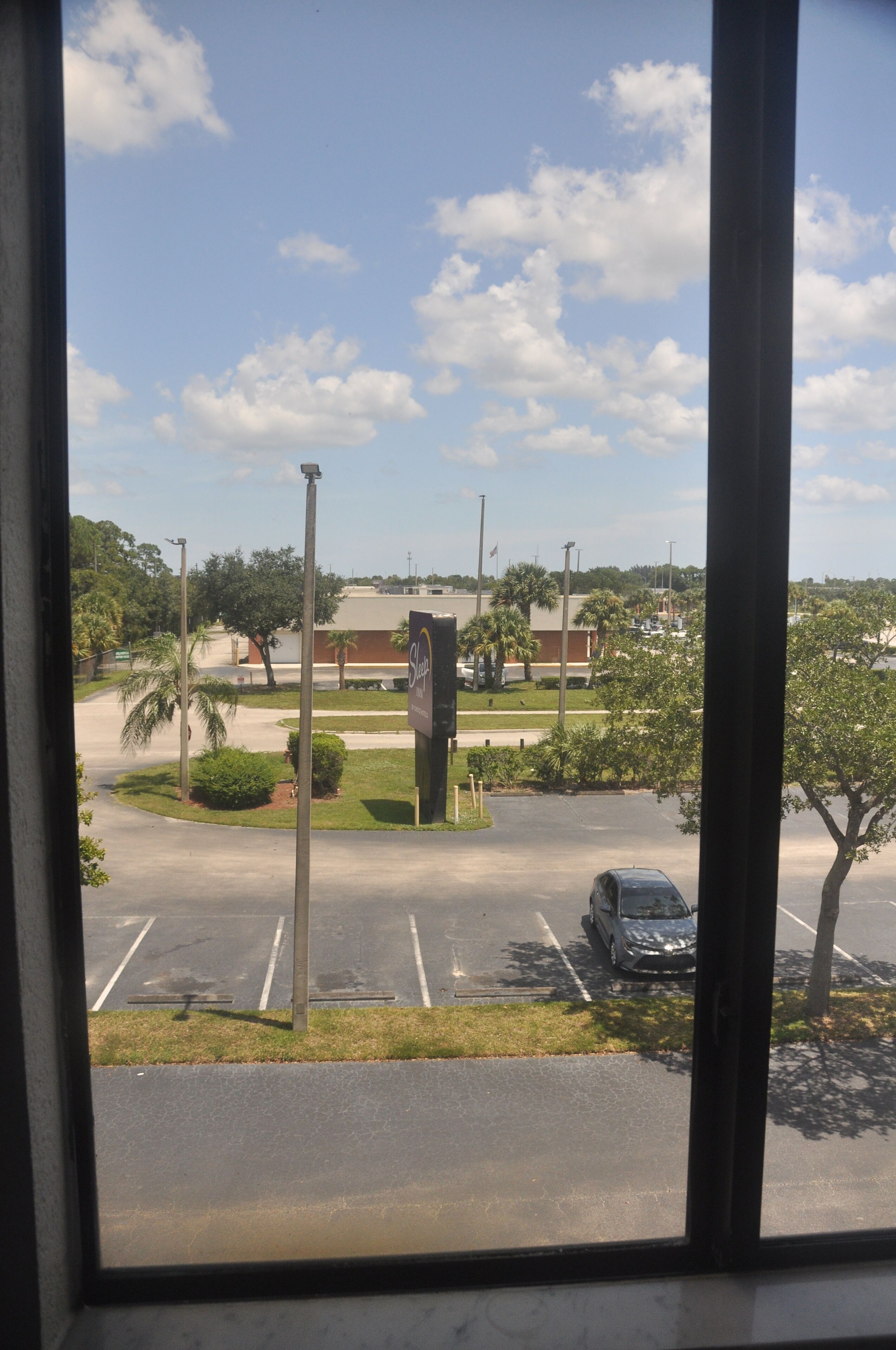 A parking lot with a building in the background, a clear sky, and a few trees.