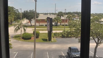 A parking lot with a building in the background, a clear sky, and a few trees.