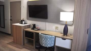 Una habitación de hotel con escritorio, silla, televisor y lámpara.