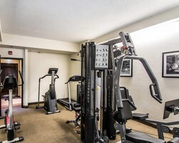 A gym with cardio machines, weightlifting equipment, and a wall-mounted exercise machine.