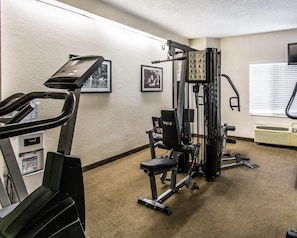 A gym with cardio equipment, weight machines, and a wall-mounted TV.
