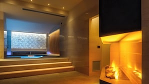A modern interior with a fireplace, a seating area with a view, and a staircase leading to a balcony. - Hotel Sangallo Palace (Perugia)
