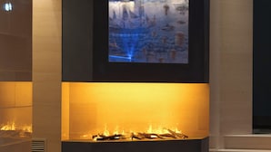 A modern interior with a fireplace, a pool, and a large screen displaying a cityscape. - Hotel Sangallo Palace (Perugia)