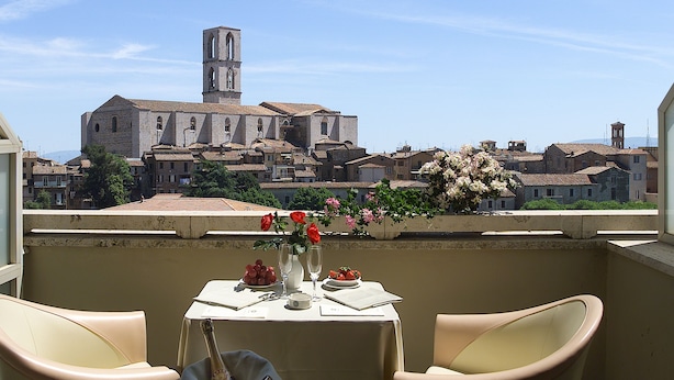 A balcony with a table set for two, overlooking a historic town with a prominent tower. - Hotel Sangallo Palace (Perugia)