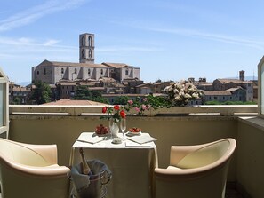 A balcony with a table set for two, overlooking a historic town with a prominent tower. - Hotel Sangallo Palace (Perugia)
