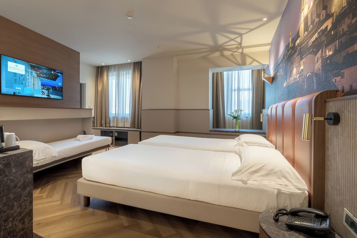 A hotel room with two beds, a flat-screen TV, a wooden headboard, a marble side table, and a telephone.