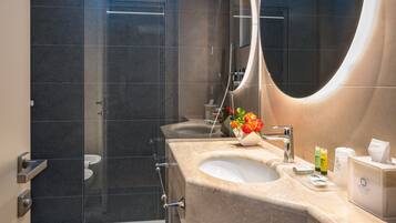 A modern bathroom with a glass-enclosed shower, a large mirror, and a vanity with a sink and towel rack.